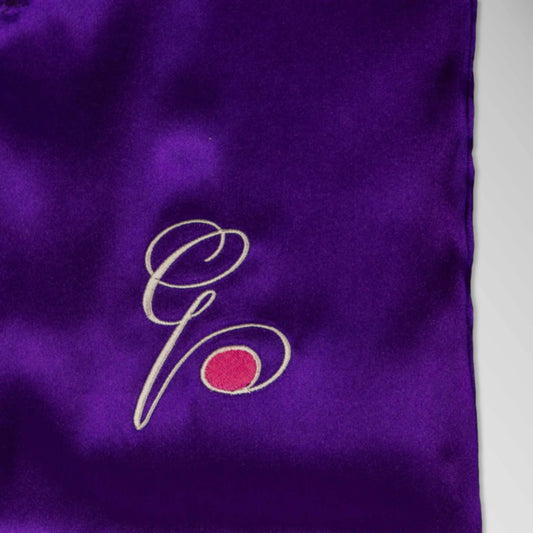 Pillowsforeplay Slip - Wider angle showing the purple slip with Elegant black cursive "G" with a pink circle and the toy insertion hole #variant:slip-color-purple-satin-slip